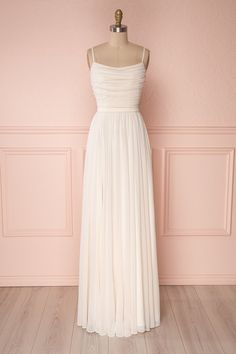 a white wedding dress on a mannequin stand in front of a pink wall