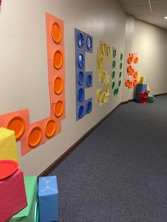 an office hallway decorated in bright colors with blocks on the wall and toys sitting on the floor