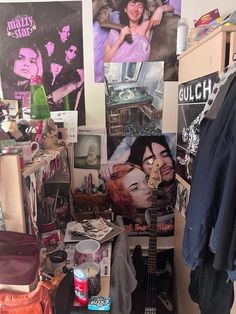 a room filled with lots of clutter and posters on the wall, including a guitar