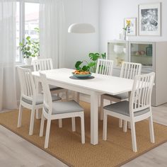 a dining table with four chairs and a bowl of fruit on it