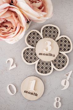 a flower and numbers are on the table next to some pink flowers, which have been cut out from wood