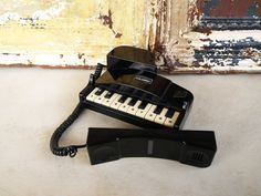 an old black phone sitting on top of a white counter next to a piano keyboard