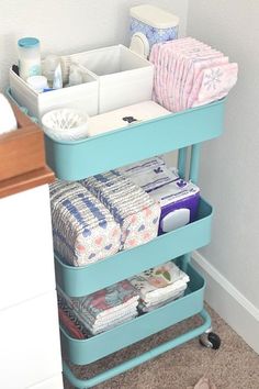 a blue cart filled with diapers next to a bathroom sink and toilet paper on the floor