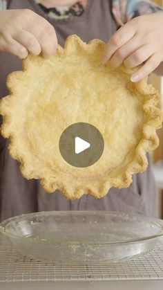 a person holding up a pie crust in front of a pan on a stove top