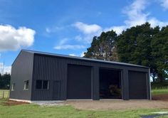 two garages with one door open in the middle of a grassy area next to trees