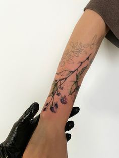 a woman's arm with flowers and leaves on the left side of her body