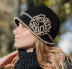 a woman wearing a black crochet hat with an intricate design on the brim