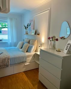 a bedroom with a bed, dresser and mirror in the corner next to a window