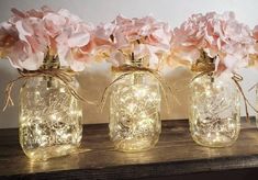 three mason jars filled with pink flowers and string lights