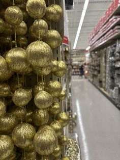 gold ornaments are hanging from the ceiling in a grocery store's aisle line as people walk by