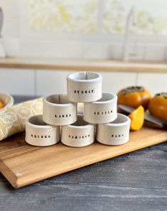 six white ceramic bowls sitting on top of a wooden cutting board next to oranges