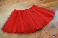 a red tutu skirt on the floor with a wooden floor in the foreground