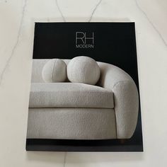 a white couch sitting on top of a marble floor next to a black book cover