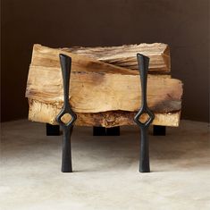 two black handles are on the legs of a wooden bench made out of tree trunks