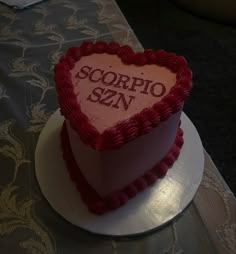 a heart shaped cake with the word scorpio sein on it sitting on a table