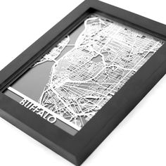 a black and white photo of a city map in a shadow frame on a table