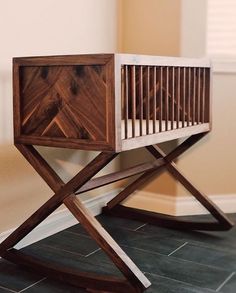 a wooden crib sitting on top of a black tile floor