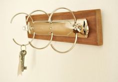 a wall mounted key holder with three rings and two keys hanging from it's sides