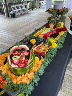 an assortment of fruits and vegetables laid out on a long table with black cloths