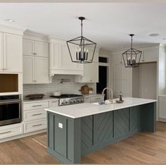 a large kitchen with an island in the middle and two pendant lights hanging from the ceiling