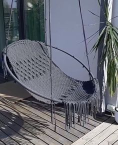 a black hammock hanging on a wooden floor next to a potted plant