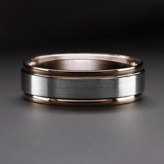 two tone gold and silver wedding band with brushed edges on a dark grey background, close up