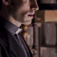 a man in a black suit and white collared shirt looking off into the distance