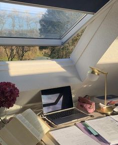 an open laptop computer sitting on top of a desk next to a book and lamp