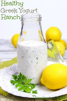 a bottle of yogurt next to lemons and parsley on a plate