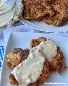 two white plates topped with meat covered in gravy