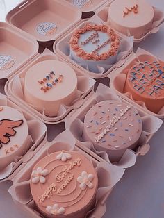 an assortment of decorated cakes in trays on a white table top with the words happy birthday written on them