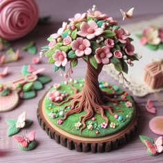 there is a cake decorated like a tree with pink flowers on it and butterflies flying around