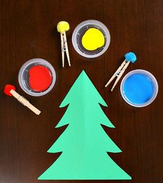 the paper christmas tree is surrounded by paints and brushes