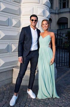 a man and woman standing next to each other in front of a white building wearing sunglasses