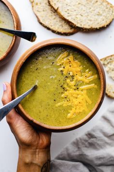 a person holding a bowl of soup with crackers on the side