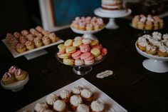 a table topped with lots of different types of cakes and cupcakes on top of plates