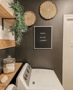 a washer and dryer sitting in a room next to a shelf with plants on it