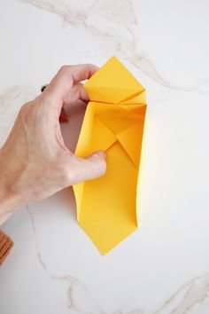 someone is folding up an origami piece on the table to make it look like he's holding something in his hand