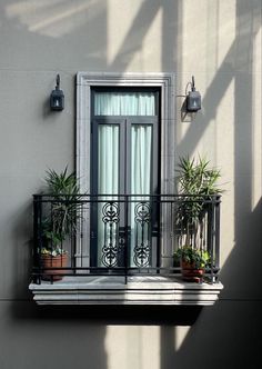 a balcony with potted plants on the balconies and an open door to another room