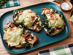 three pieces of bread with cheese and spinach on them sitting on a blue plate