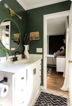 a bathroom with green walls and white cabinets is pictured in this image, there is a mirror on the wall above the sink