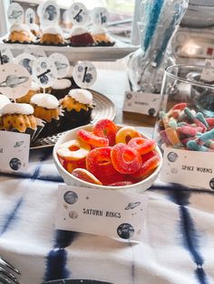 a table topped with cupcakes covered in frosting next to other desserts