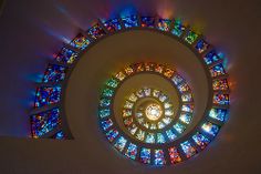 a spiral stained glass window in the center of a building with multiple colors on it