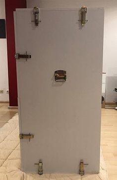 a white refrigerator sitting on top of a wooden floor next to a red and white wall