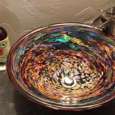 a glass bowl sink sitting on top of a counter next to a faucet