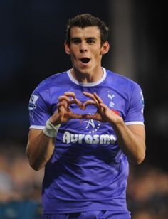 a soccer player is making a heart sign with his hands as he stands on the field