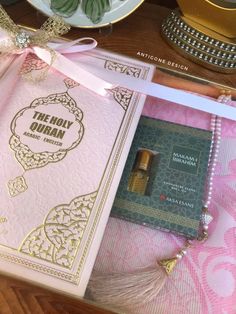 a pink and gold card with a tassel on it sitting next to a plate