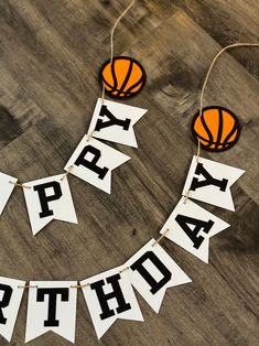 a happy birthday banner with basketballs hanging from it's sides on a wooden floor