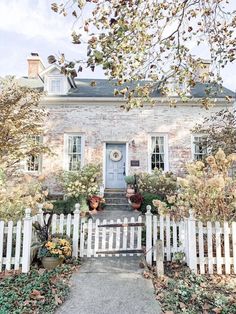 a white picket fence in front of a brick house with potted plants on it