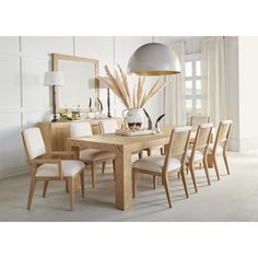 a dining room table with chairs and a large mirror on the wall in front of it